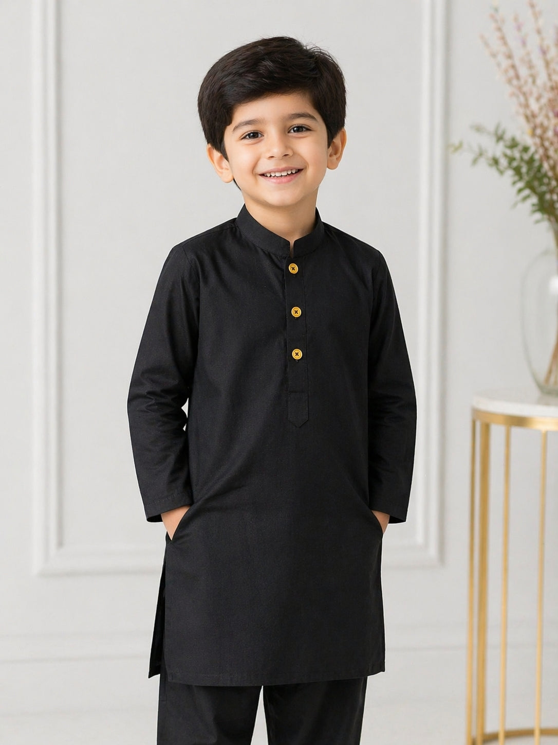 Young boy wearing a black Shalwar Kameez with yellow buttons